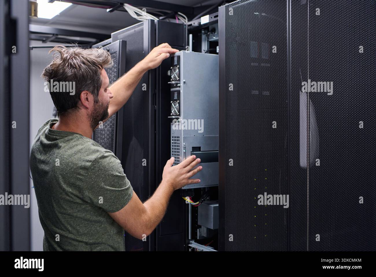 IT technician installing server hardware in a data center rack performing maintenance and configuration Stock Photo