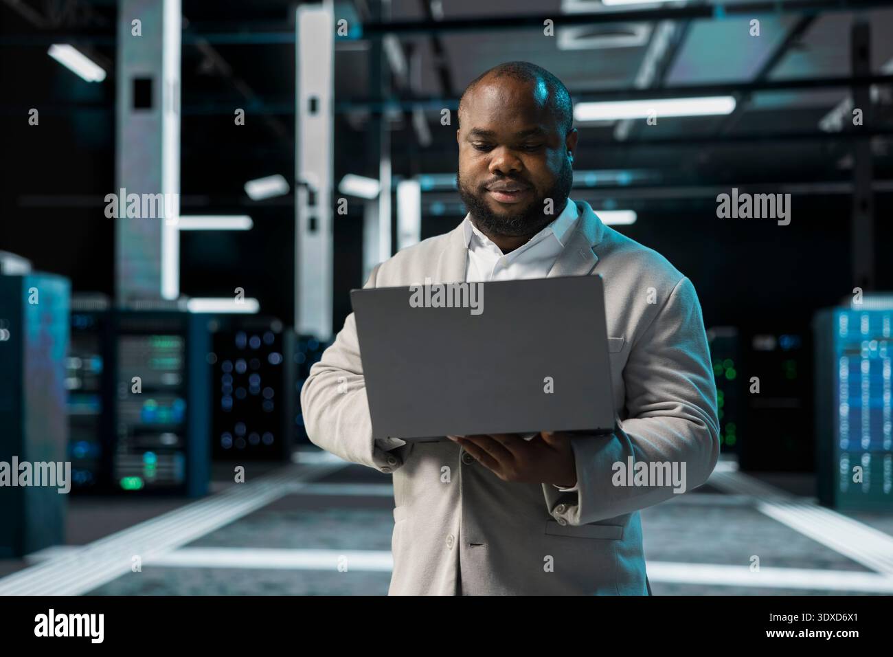 Computer scientist in data center updating systems using laptop, protecting equipment from damaging software errors. Server hub employee using notebook, looking for bugs causing gear to slow down Stock Photo
