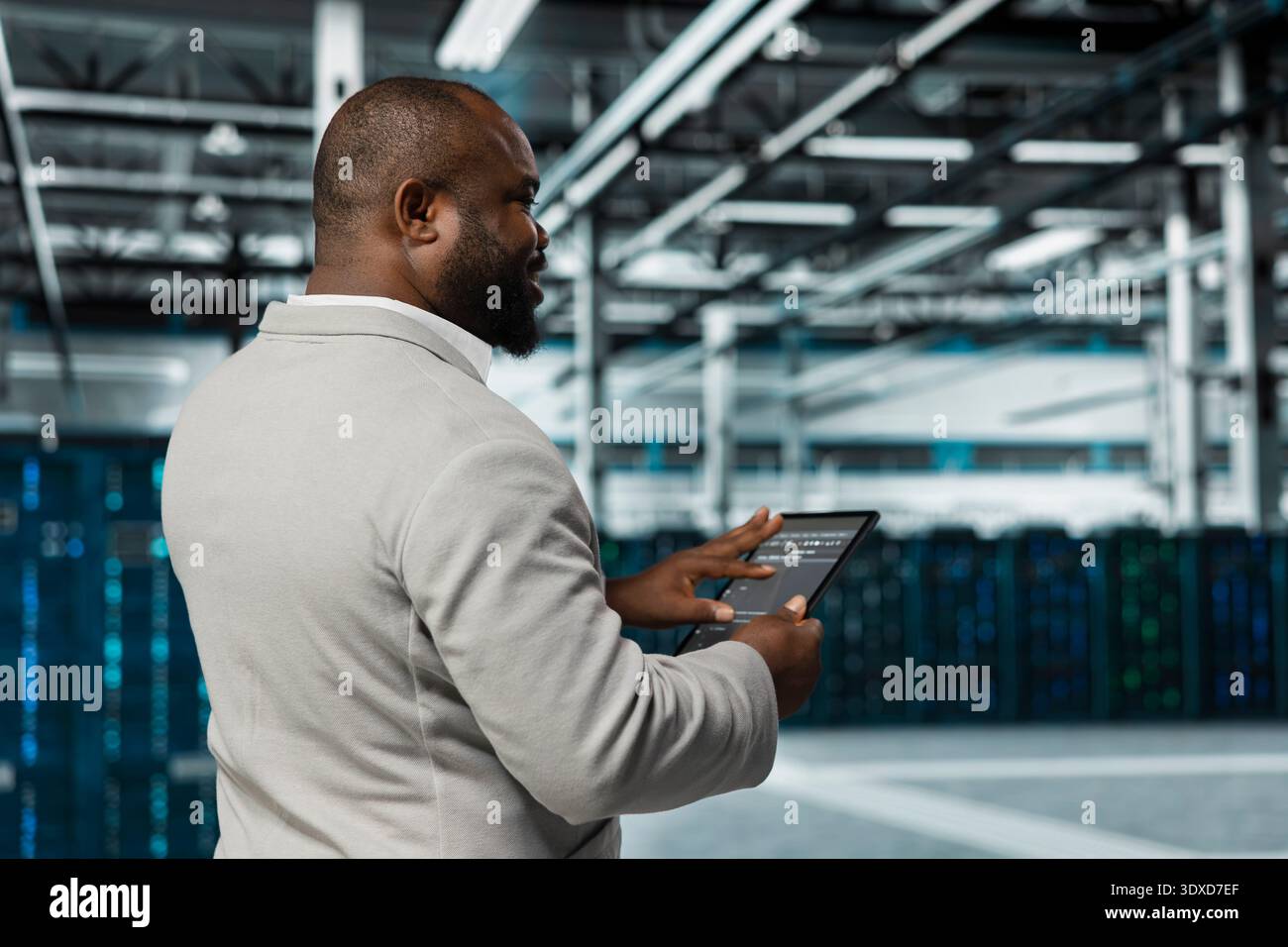 System administrator walking in data center running lines of code on tablet, troubleshooting rackmounts. Employee using programming scripts on device in server farm, optimizing performance Stock Photo