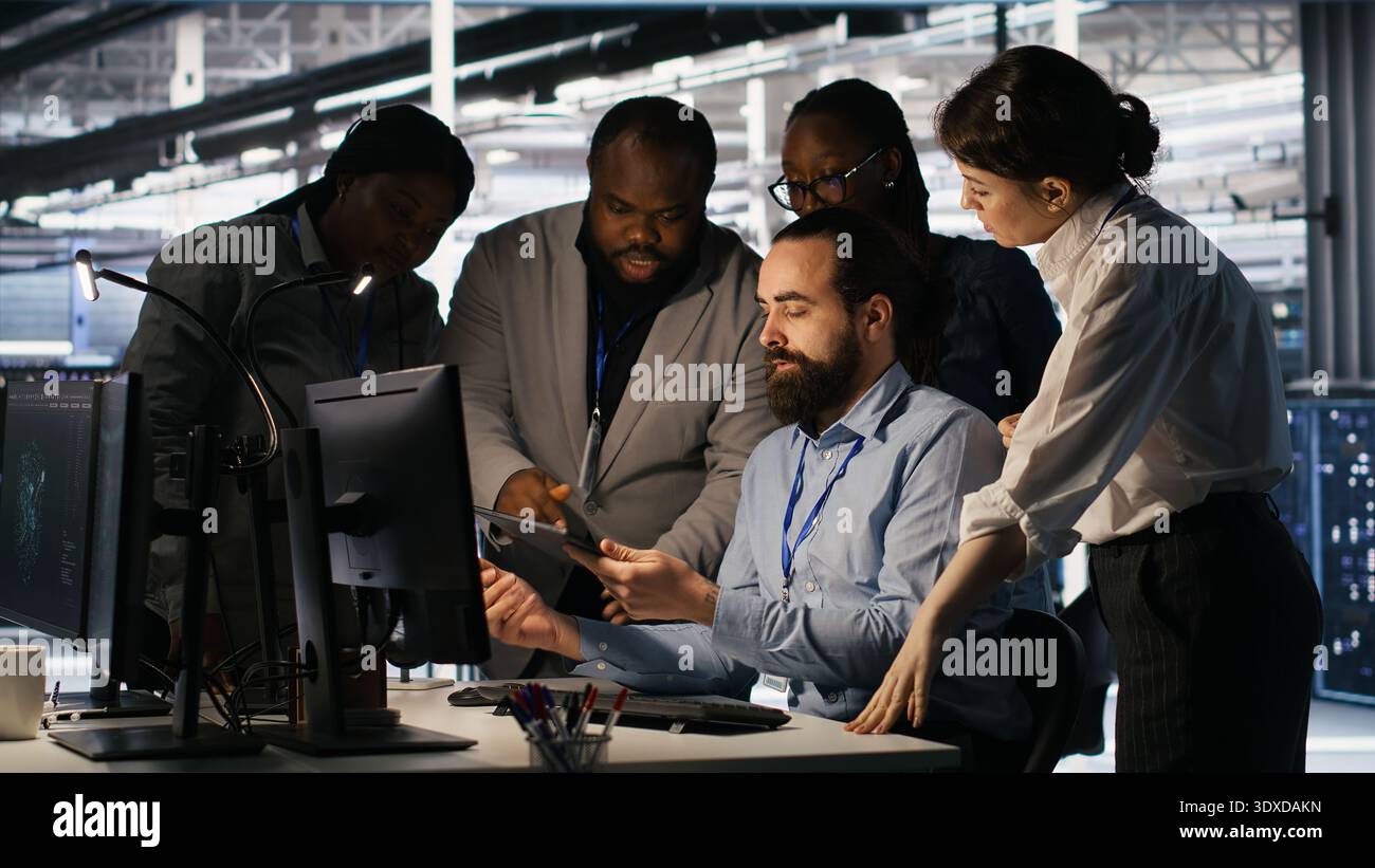 Data center system administrators performing maintenance on supercomputers used for AI processing. Team managing server hub rigs used for deep learning training, looking over business charts, camera A Stock Photo