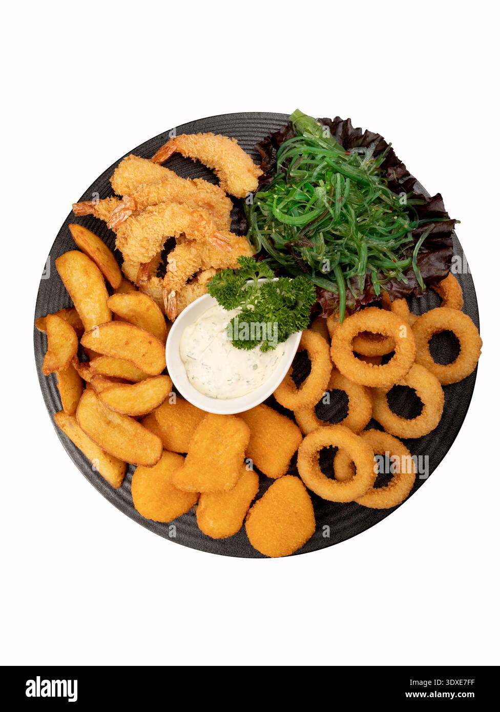 Assorted fried seafood and snacks on a black plate with herbs. Isolated on white background, top view. Stock Photo