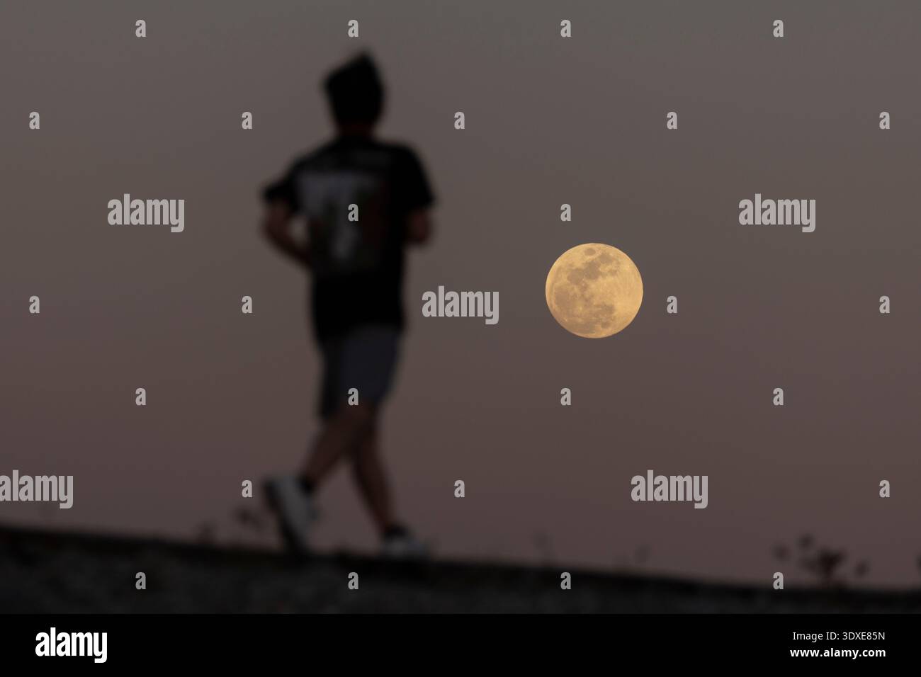 The full Worm Moon rises over Los Angeles on March 2, 2026, as a man ...