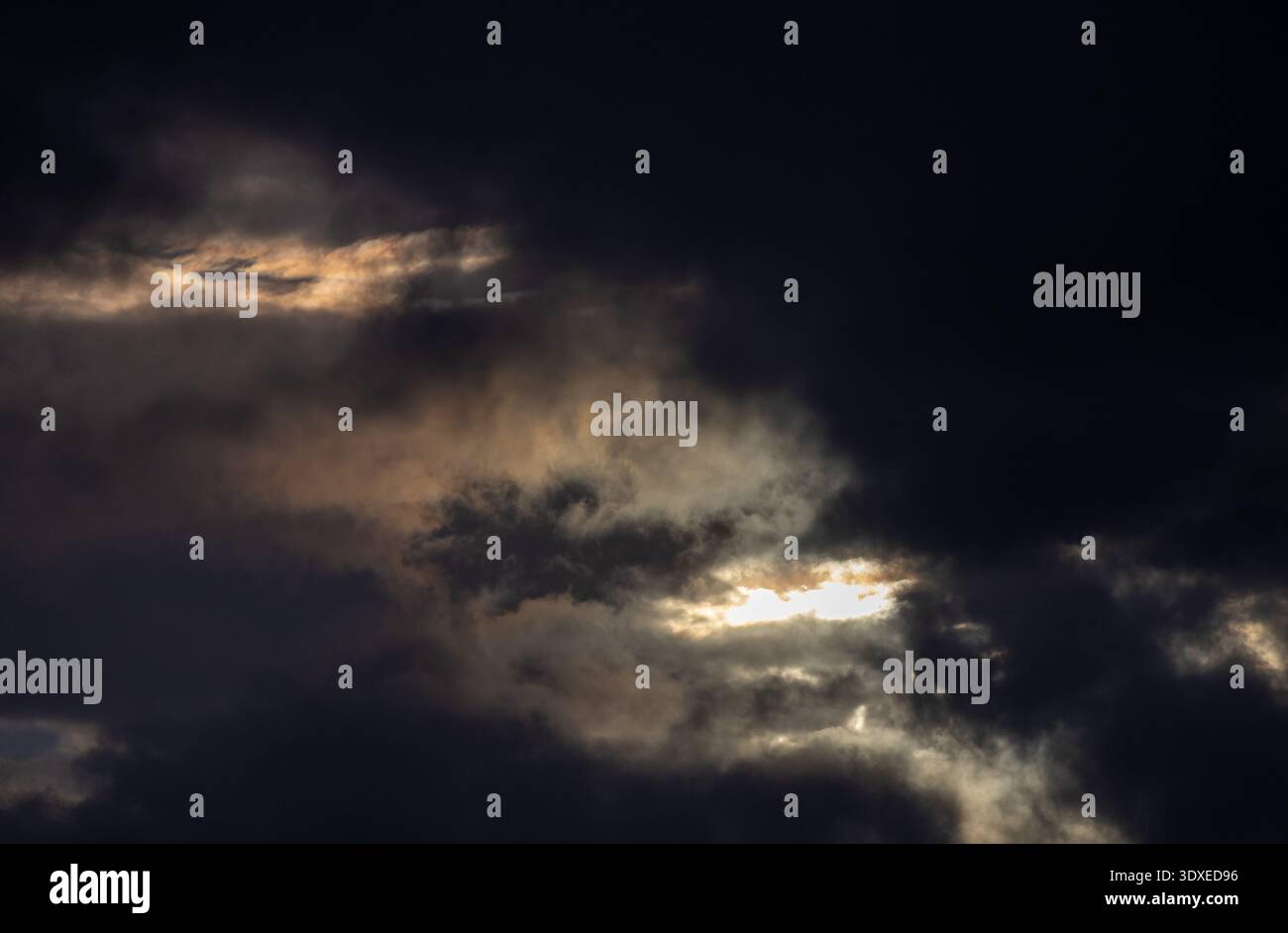 Sun breaking through dark storm clouds Stock Photo