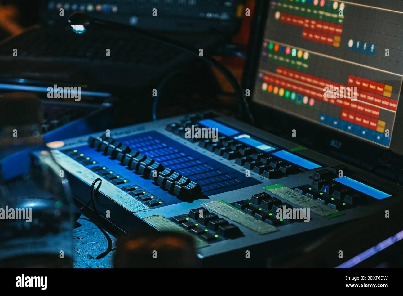 Riga, Latvia - February 28, 2026:Close-up of a professional lighting control console with illuminated faders and digital interface screens in a dark s Stock Photo