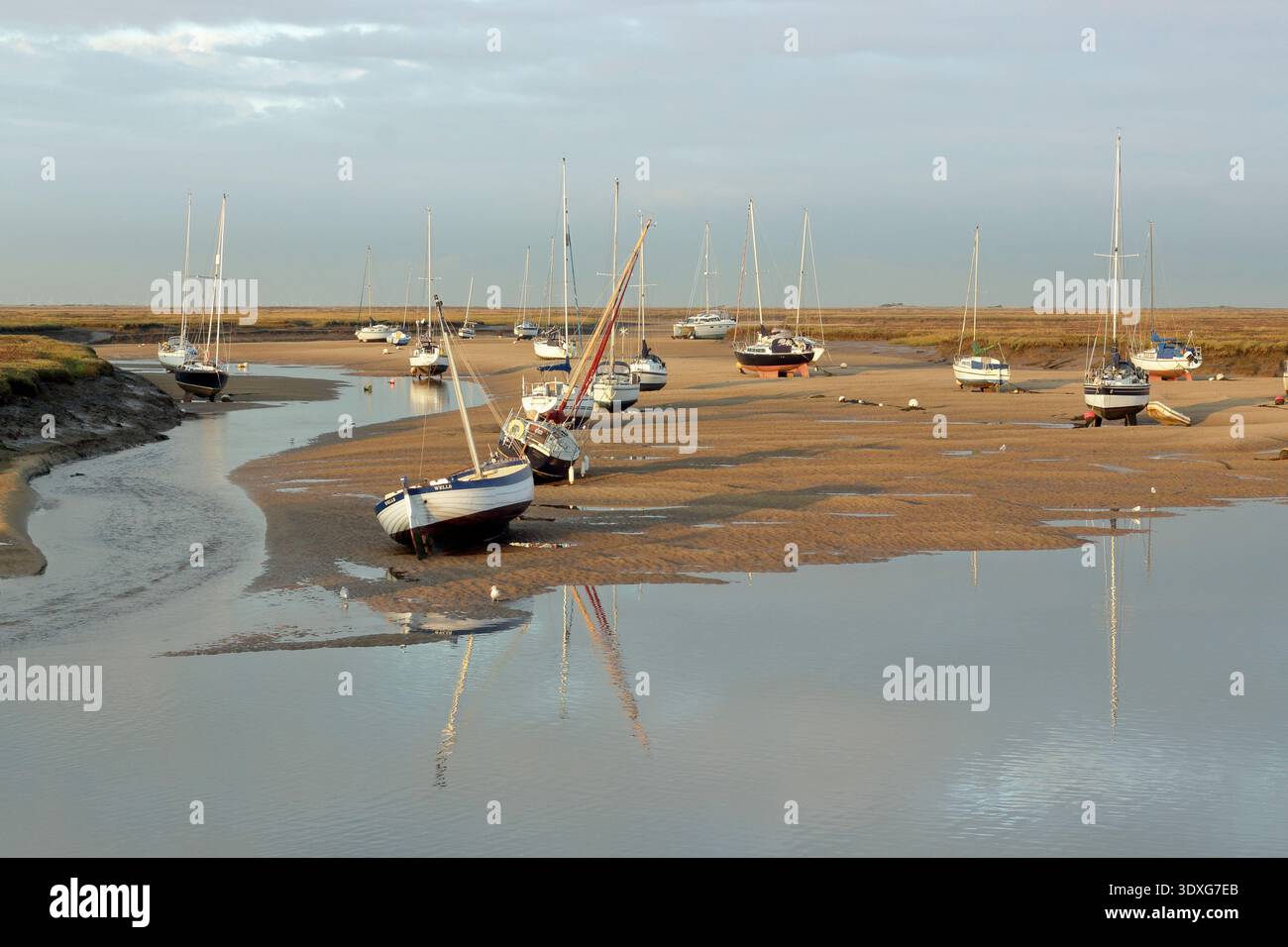 Wells next the Sea coastline, North Norfolk. Boats at low tide in the creek at Wells next the Sea harbour. Scenic coastline, Norfolk, UK. Stock Photo