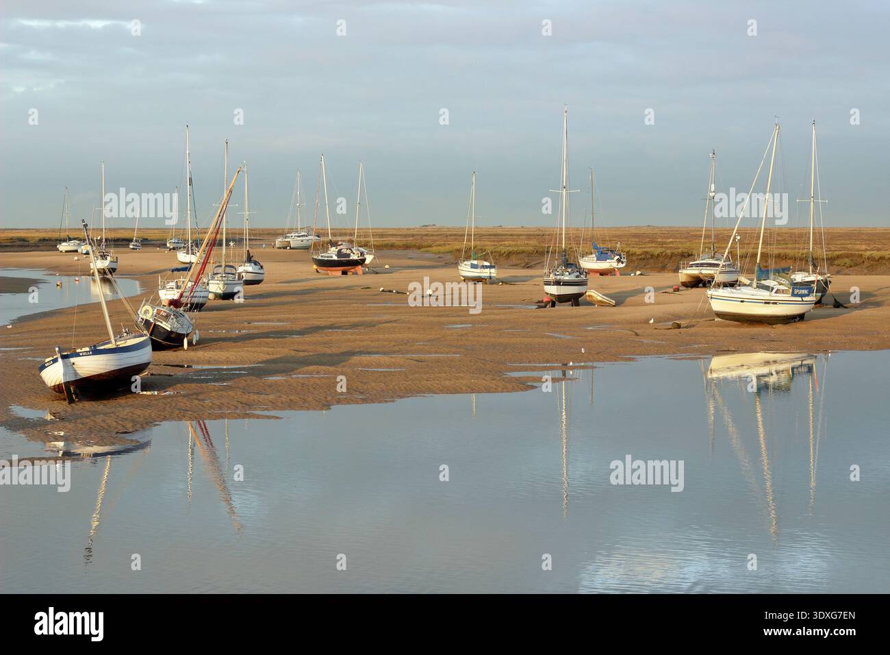 Wells next the Sea coastline, North Norfolk. Boats at low tide in the creek at Wells next the Sea harbour. Scenic coastline, Norfolk, UK. Stock Photo