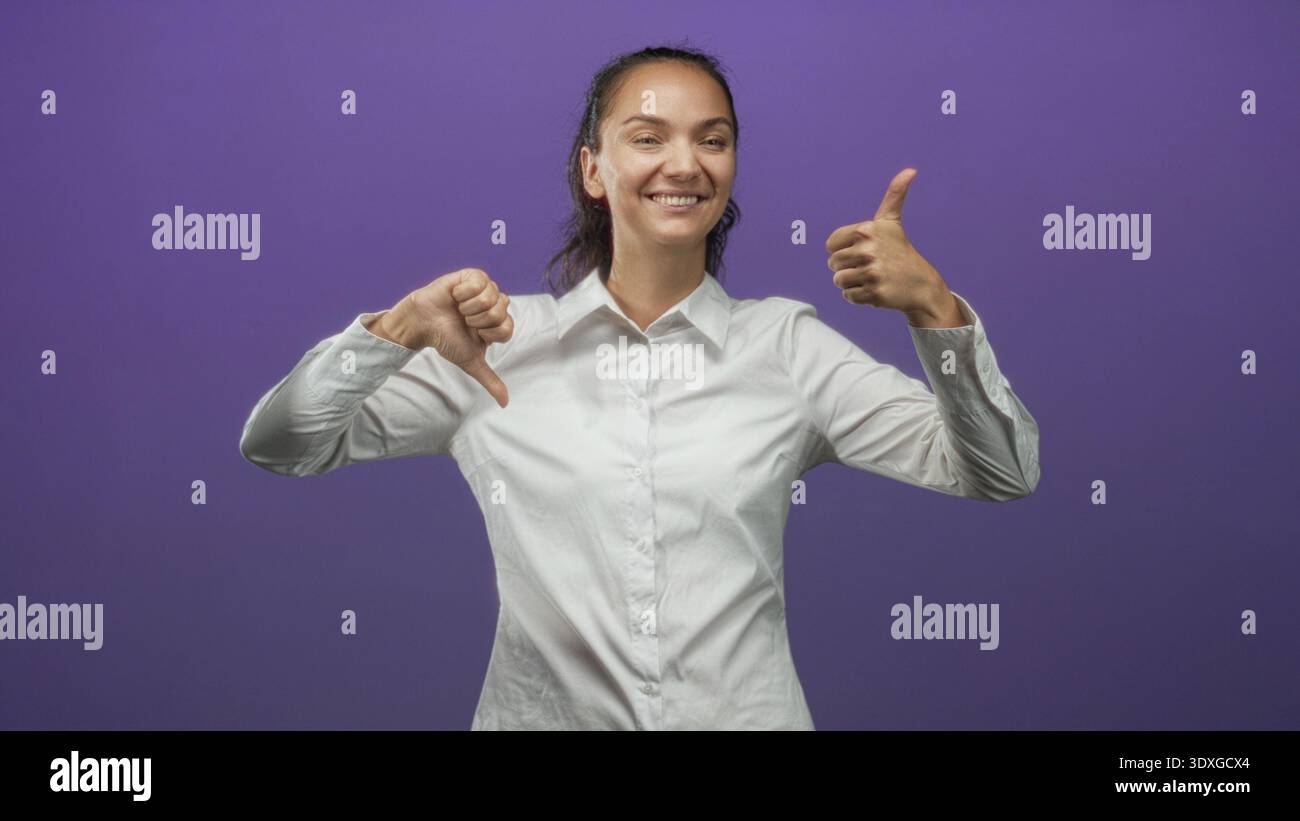 Woman showing thumbs up and thumbs down gestures in purple studio ...