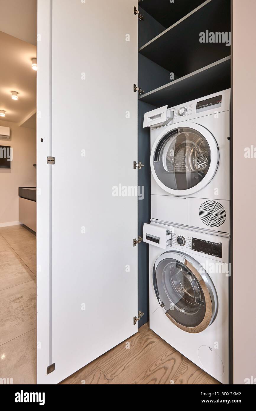 Compact laundry closet with stacked washing machine and dryer behind ...
