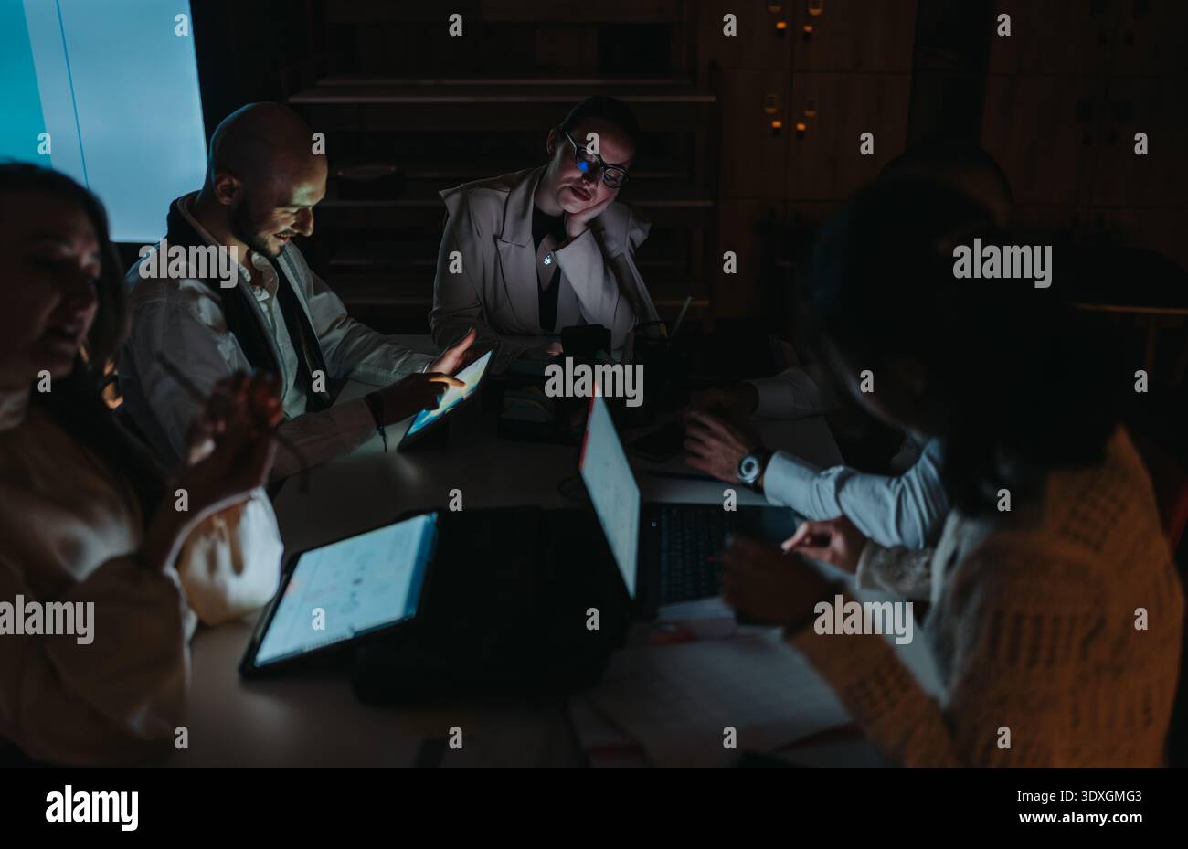 Business meeting with a diverse team collaborating around a table with laptops and tablets Stock Photo