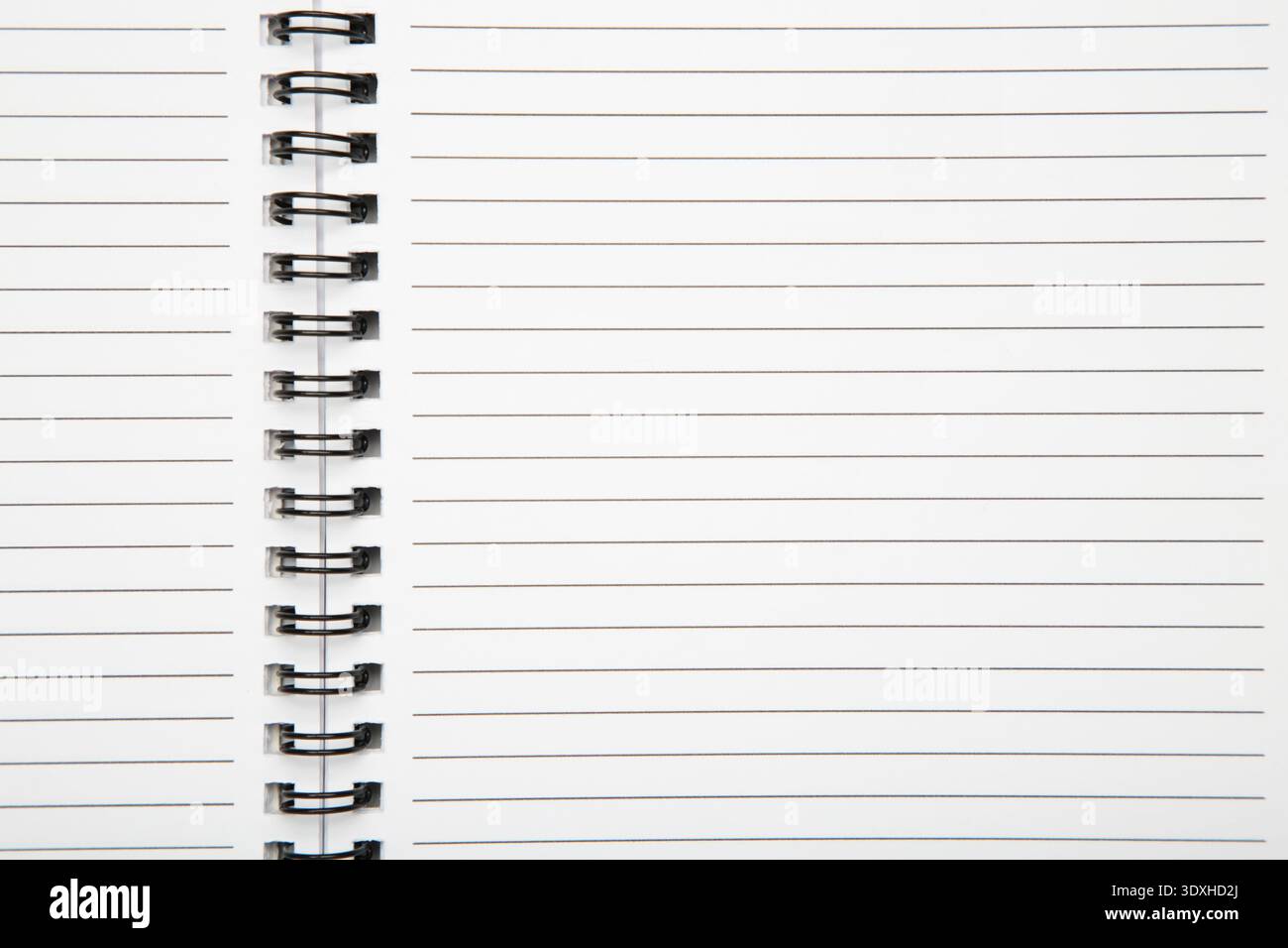 Macro shot of a black metal double-wire spiral binding on white notebook. Top view Stock Photo