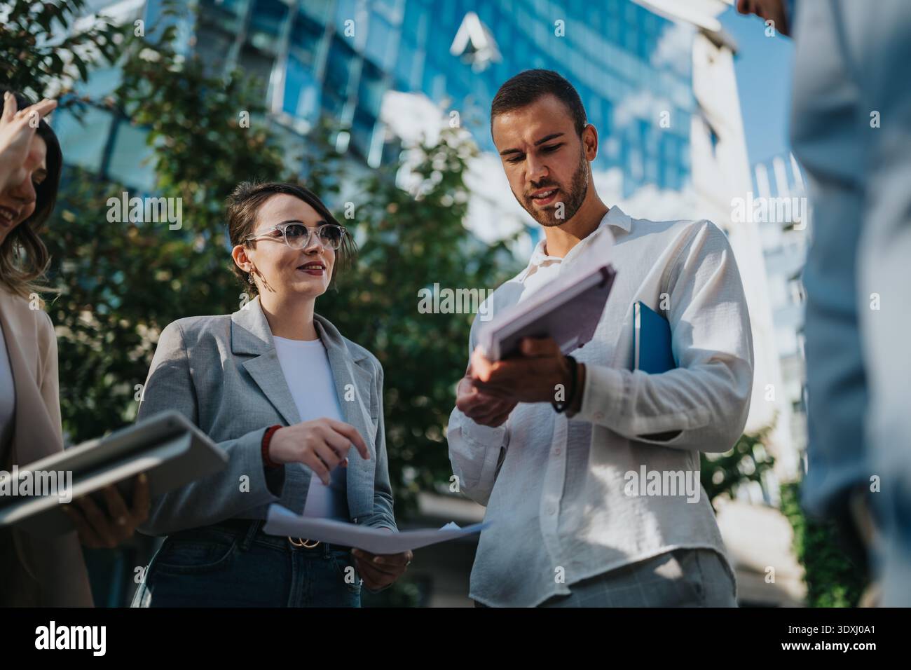 Business colleagues discuss documents outdoors on a sunny spring day in the city Stock Photo