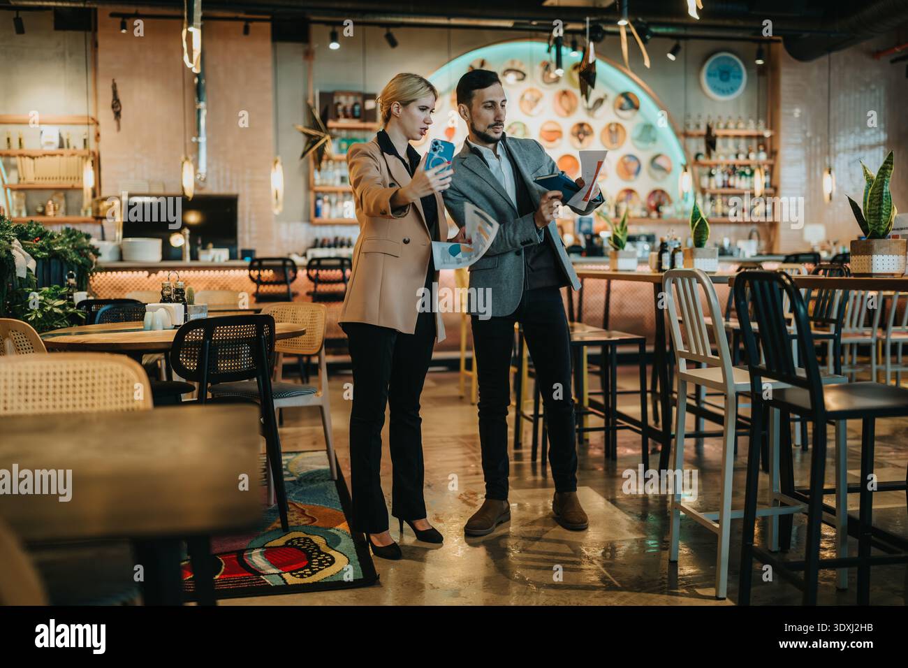 Business partners review documents in a modern cafe setting during a casual meeting Stock Photo