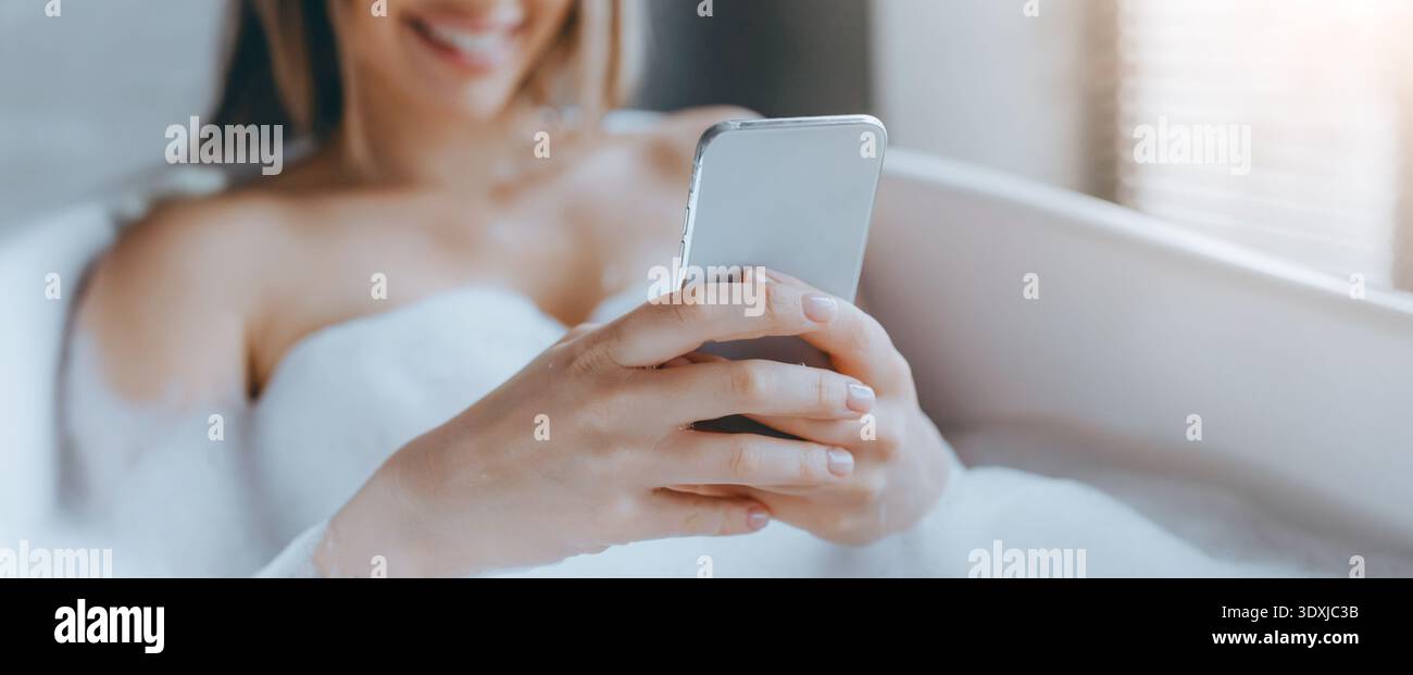 Woman Relaxing in Bathtub While Using Smartphone During Daytime Stock Photo