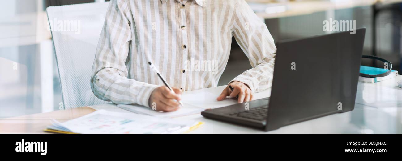 Happy Young Latin Businesswoman Takes Notes While Working at Modern Office Computer Stock Photo