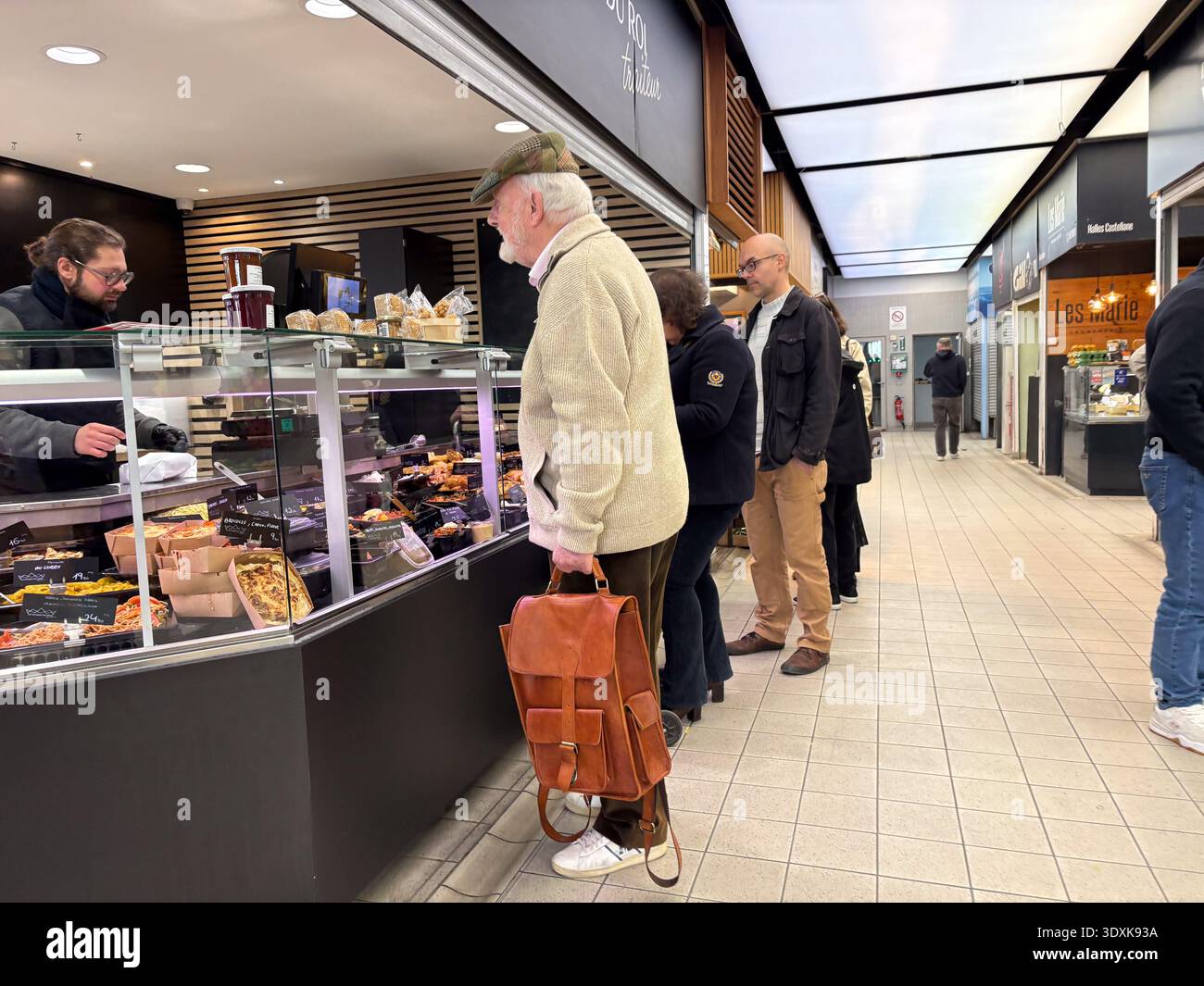 Customers queueing at a deli counter in a French indoor food hall ...