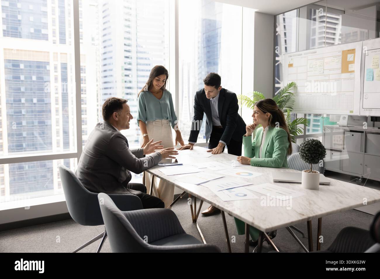 Multiethnic startup developers team gather around boardroom table brainstorming insights Stock Photo