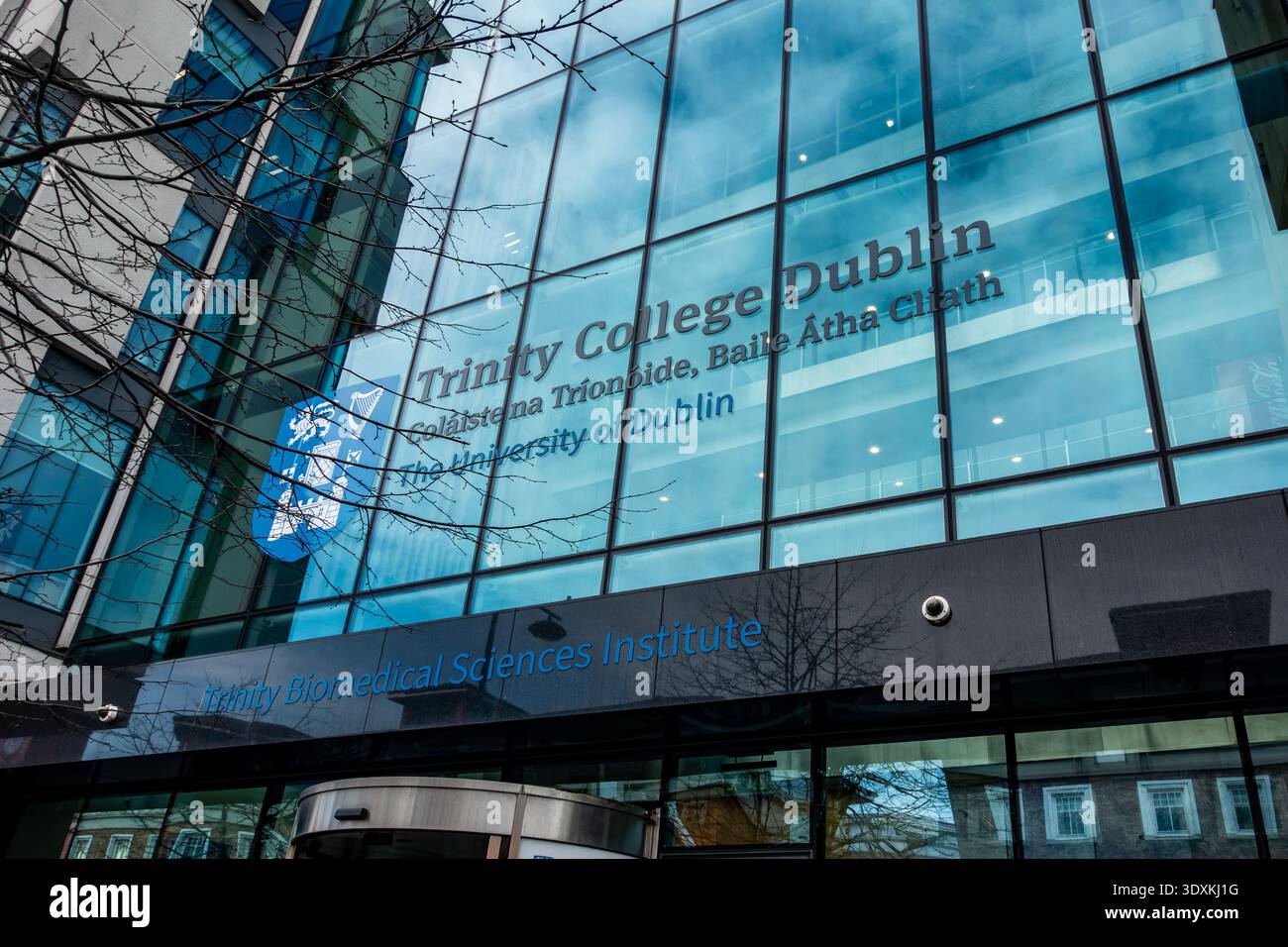 Glass facade of the Trinity Biomedical Sciences Institute, Trinity College Dublin, Ireland, featuring building signage and college crest. Stock Photo
