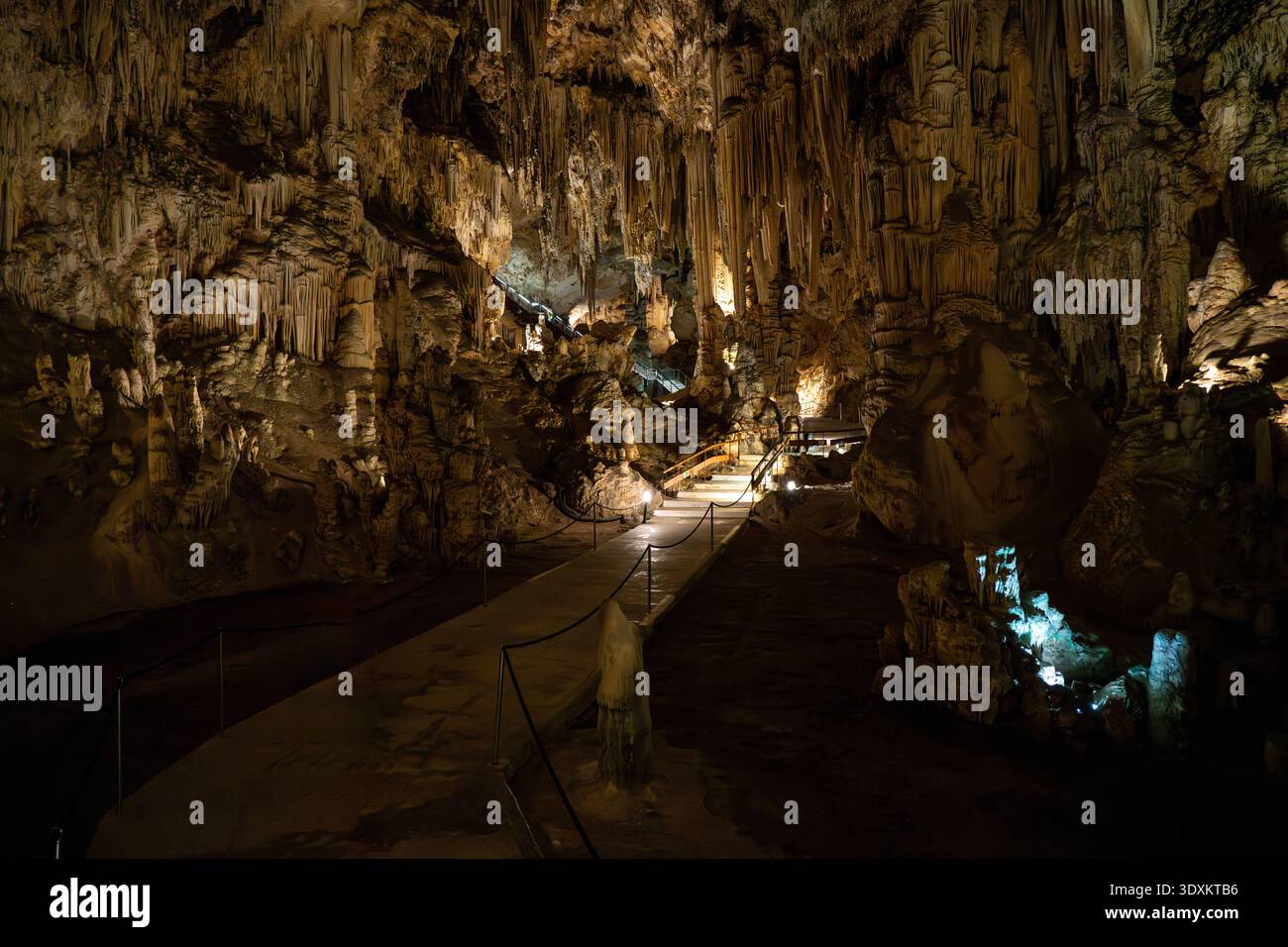 Massive calcite dripstone pillar with textured stalactites and stalagmites under cave lighting in Nerja Cave, Spain. Stock Photo