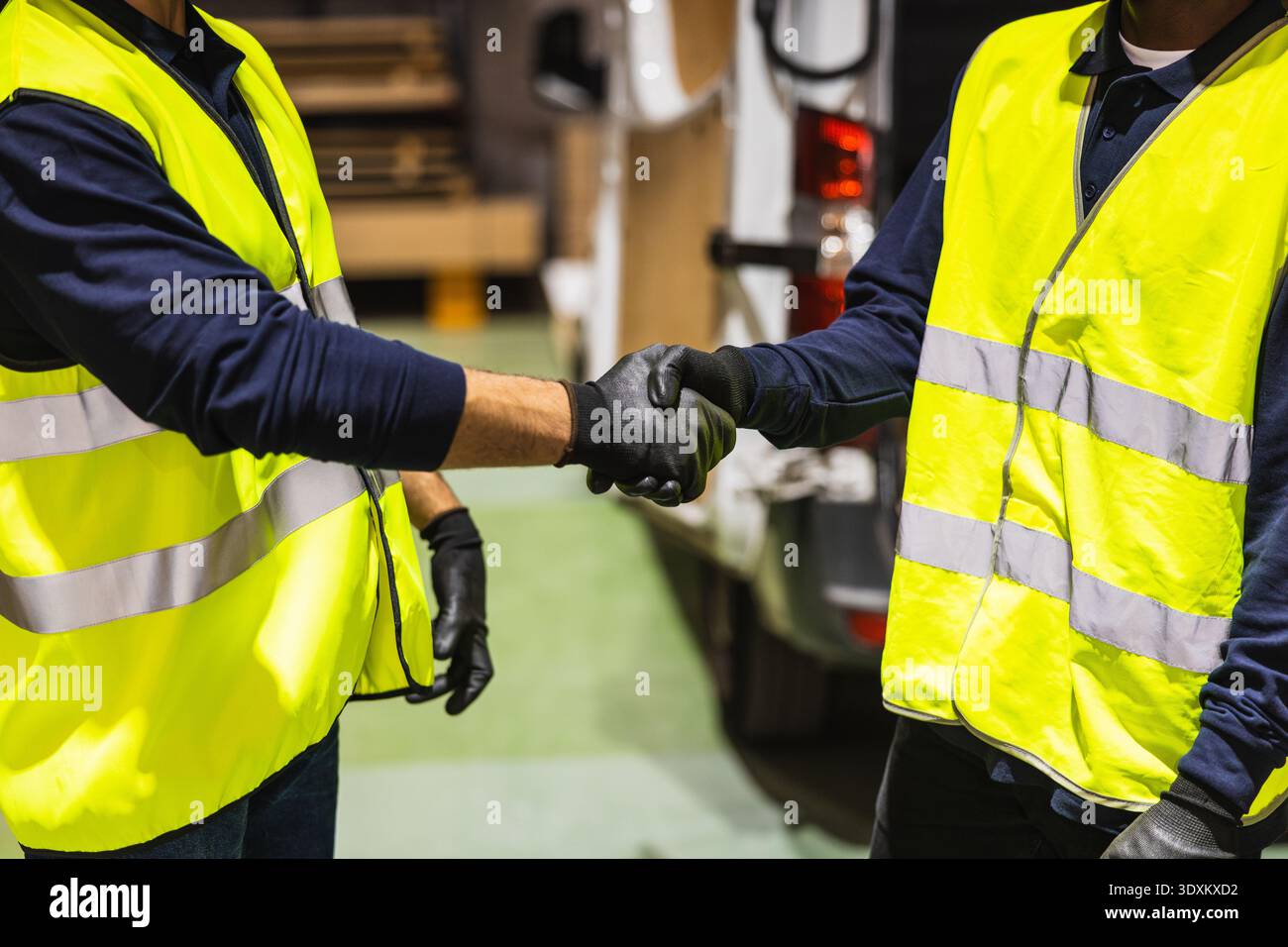 Workers shaking hands for partnership in warehouse Stock Photo
