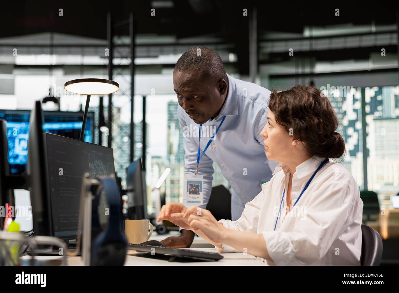 Manager supervising intern in office automating tasks using AI scripts on PC. Silicon Valley startup team leader overseeing employee using deep learning tech to speed up feature implementation Stock Photo