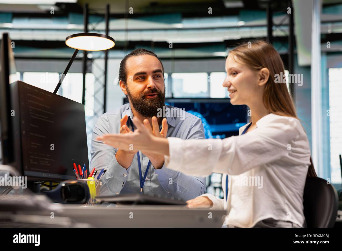 Lead engineer providing support to new programmer in software development agency. Seasoned developer explaining best practices to trainee during internship in tech startup company Stock Photo