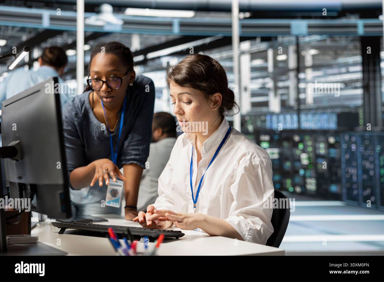 Server farm teamworking colleagues using computer to analyze facility data patterns. Data center experts working together, using programming language algorithms on PC to analyze datasets Stock Photo