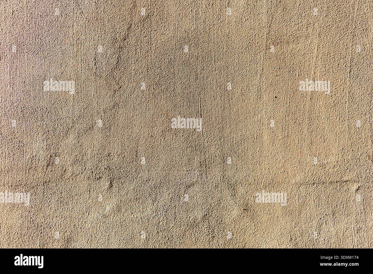 Textured beige stucco wall with subtle cracks and grain. Stock Photo