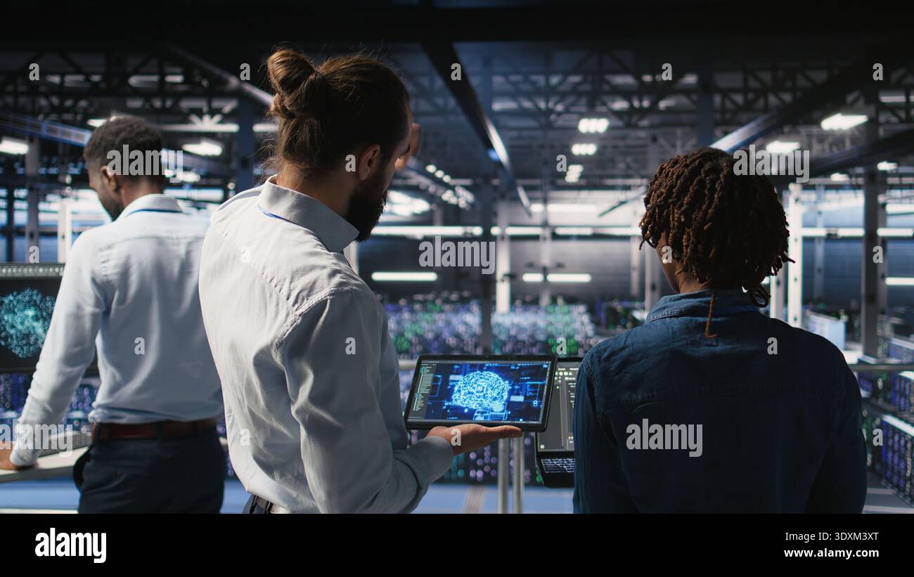 Data center engineering team doing maintenance on servers used for artificial intelligence processing. IT experts manage data center arrays used for machine learning training with tablet, Stock Photo