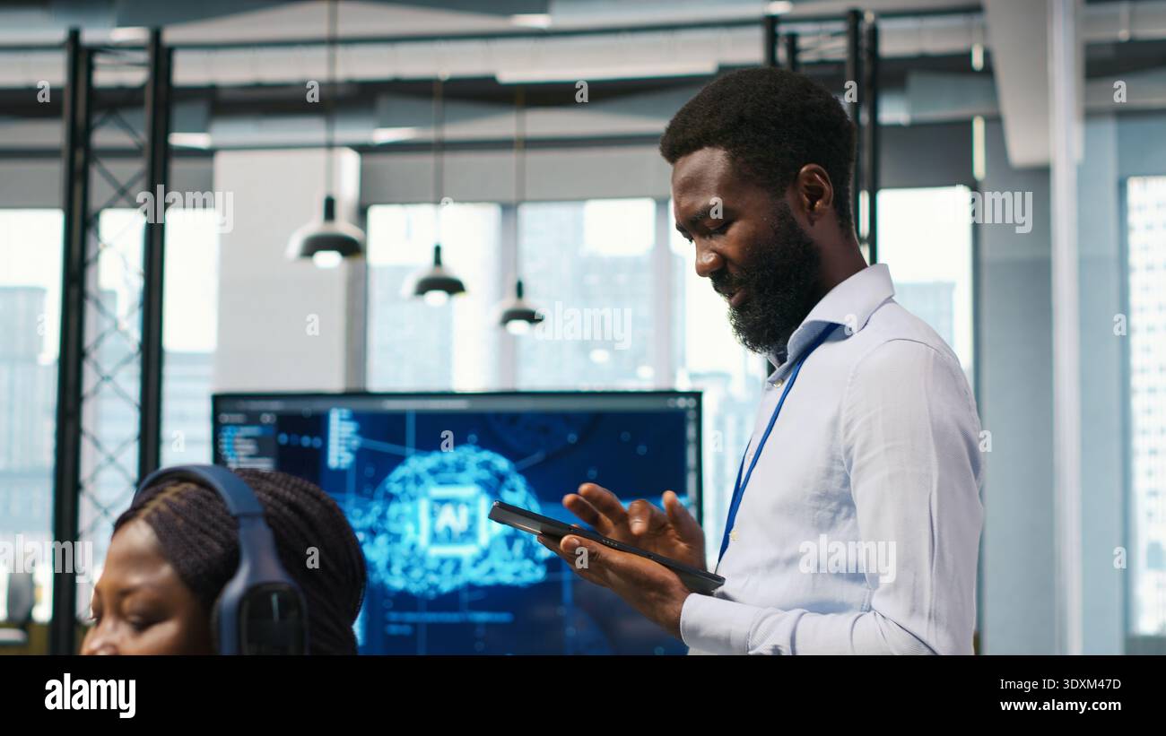 Joyous technician in office automating repetitive tasks using AI scripts. Upbeat man in workplace using artificial intelligence to speed up feature implementation, camera A Stock Photo