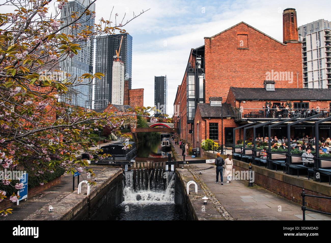 Castlefield canal basin in Manchester with narrowboats, historic brick warehouses and modern skyline, popular urban district in England. Stock Photo