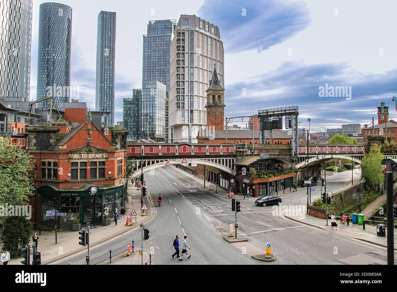 Manchester city centre skyline with railway viaduct and Atlas Bar near Deansgate Locks, modern skyscrapers and historic buildings. Stock Photo