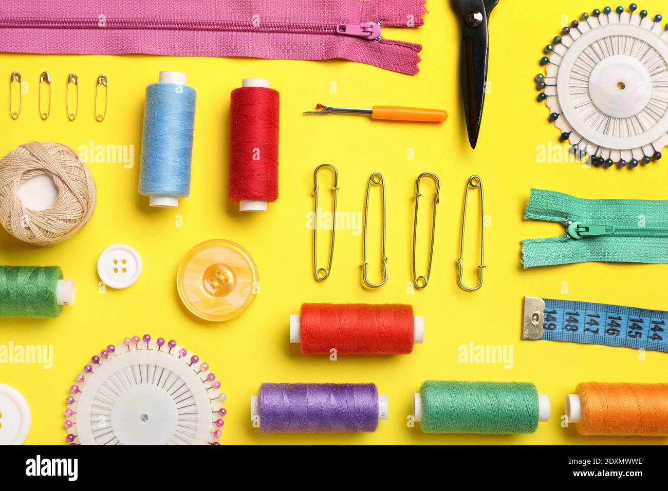 Composition with different thread spools and sewing accessories on yellow background Stock Photo