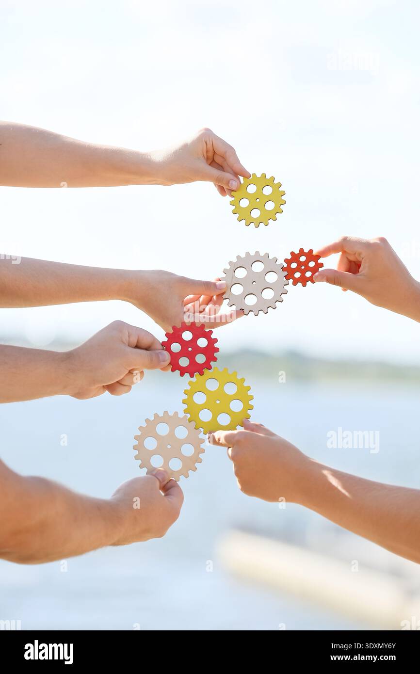 Many hands with gears outdoors Stock Photo