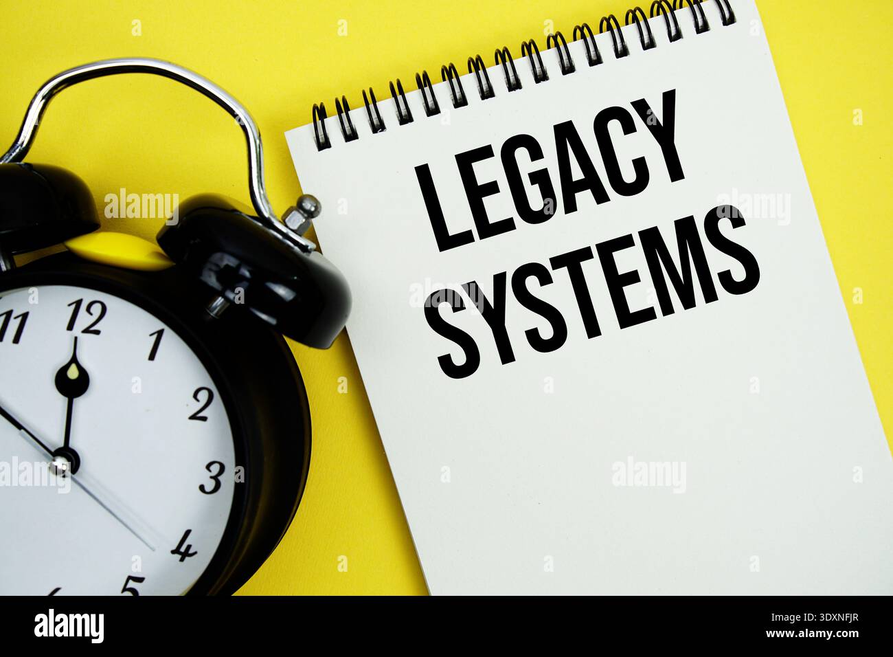 Legacy Systems text with alarm clock flat lay on yellow background Stock Photo