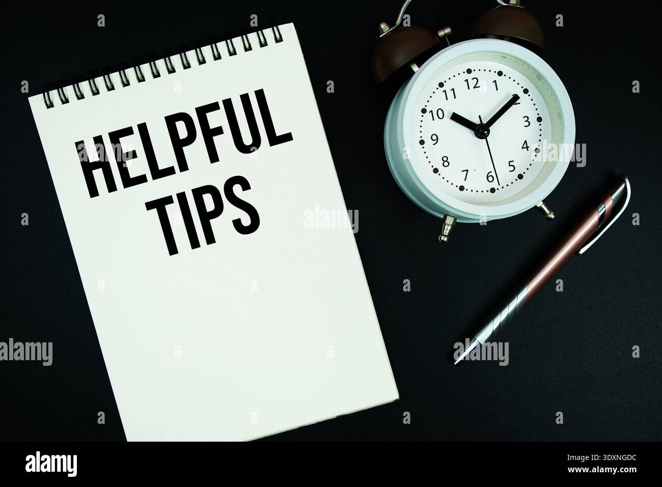 Helpful Tips text written on notepad with pen and alarm clock Stock Photo