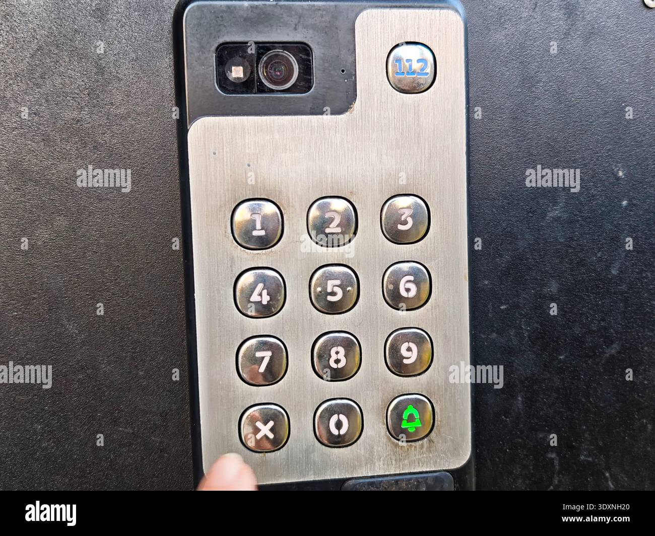 Close view of a hand entering access code on intercom keypad at an entrance for building security and door entry. Stock Photo