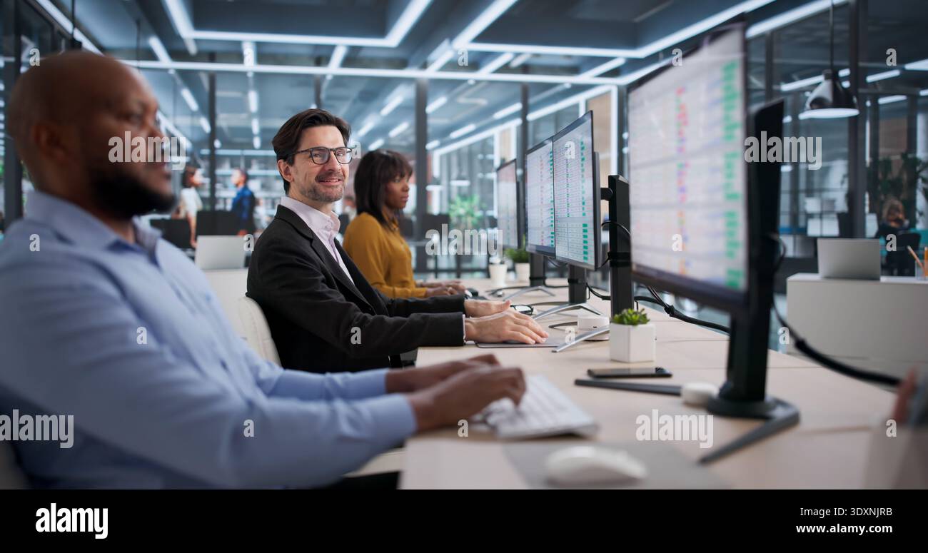 Diverse Team Of Accountants And Coders Smiling While Using Spreadsheets On Computers. Stock Photo
