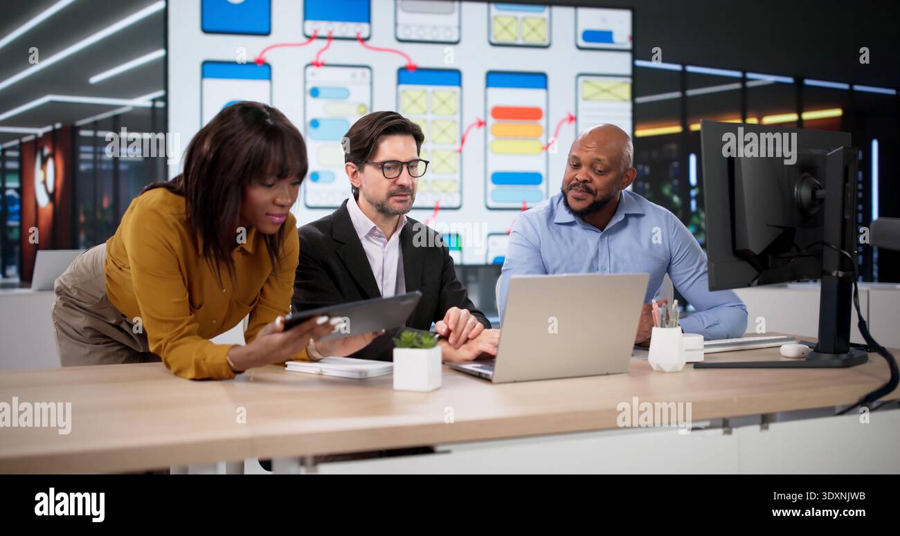 Diverse Team Of Designers And Developers Collaborates On Web Applications Using Laptops And Tablets Stock Photo
