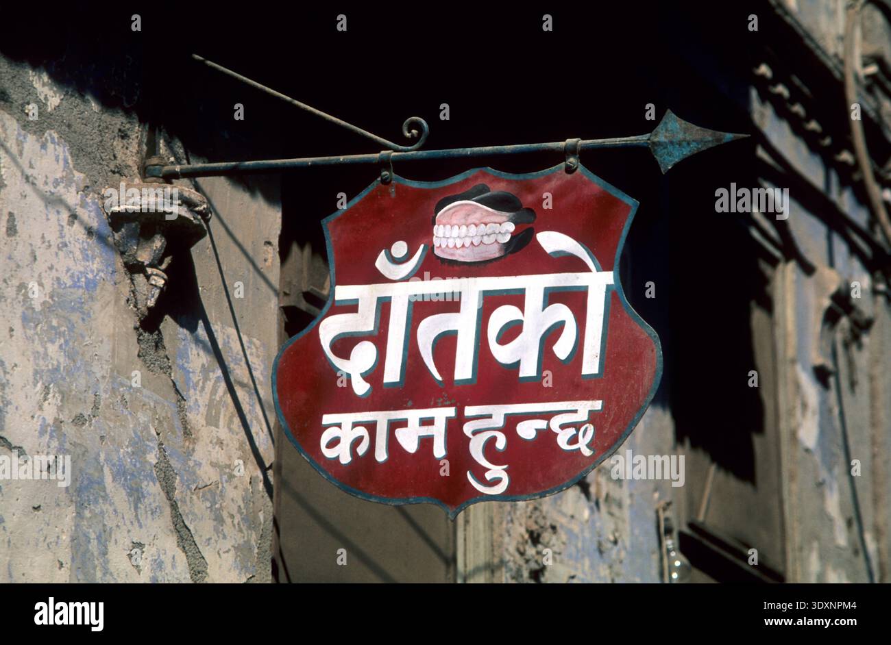 A hand-painted dental clinic sign featuring a set of dentures and Devanagari script in Kathmandu, Nepal. Stock Photo