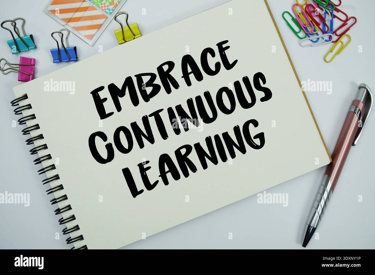 Embrace Continuous Learning text message written on notepad with stationery flat lay on white background Stock Photo
