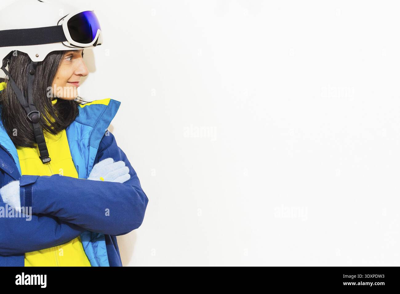 Skier young woman wearing warm padded windbreaker jacket hat ski goggles mask point index finger aside on copy space blank area travel rest spend week Stock Photo