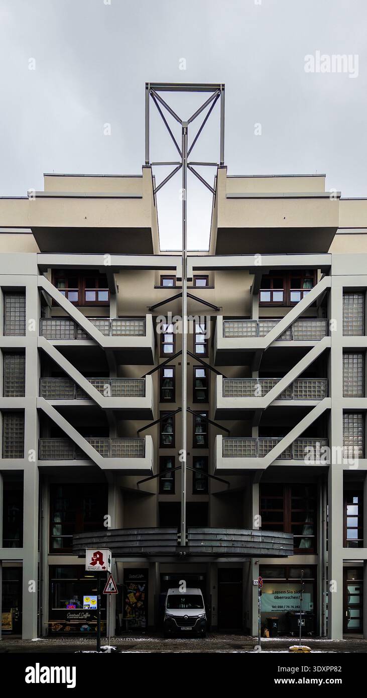 Striking symmetrical modernist apartment building in Berlin with central steel lattice tower, geometric balconies and light stairways under overcast s - Smartphone Captured Stock Image
