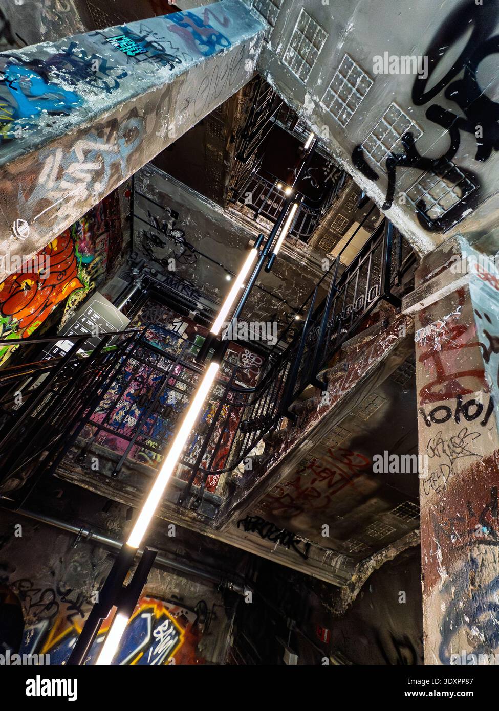 Dramatic low-angle view of graffiti-covered stairwell in Fotografiska Berlin museum, former Kunsthaus Tacheles art squat in Mitte with neon LED lights - Smartphone Captured Stock Image