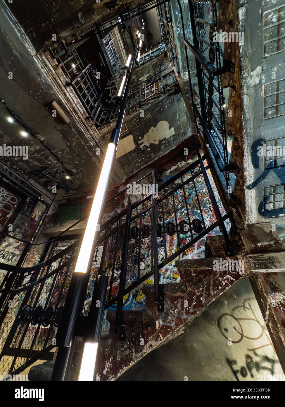 Dramatic low-angle view of graffiti-covered stairwell in Fotografiska Berlin museum, former Kunsthaus Tacheles art squat in Mitte with neon LED lights - Smartphone Captured Stock Image