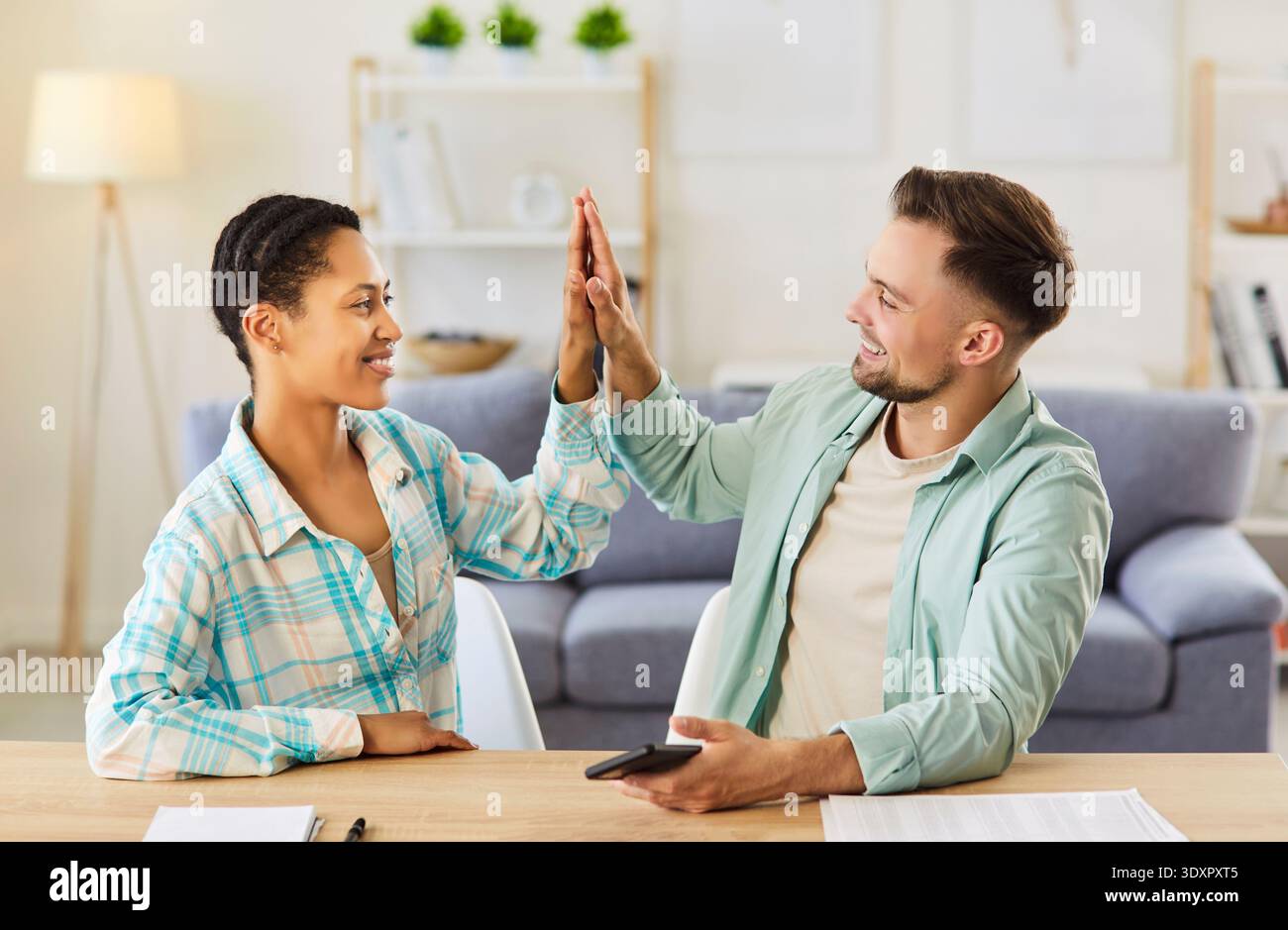 Woman and man students reaching agreement, giving high five to each other, working as friendly team Stock Photo