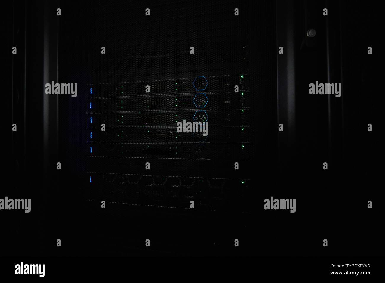Server rack with illuminated network hardware and blinking LEDs in a dark data center Stock Photo