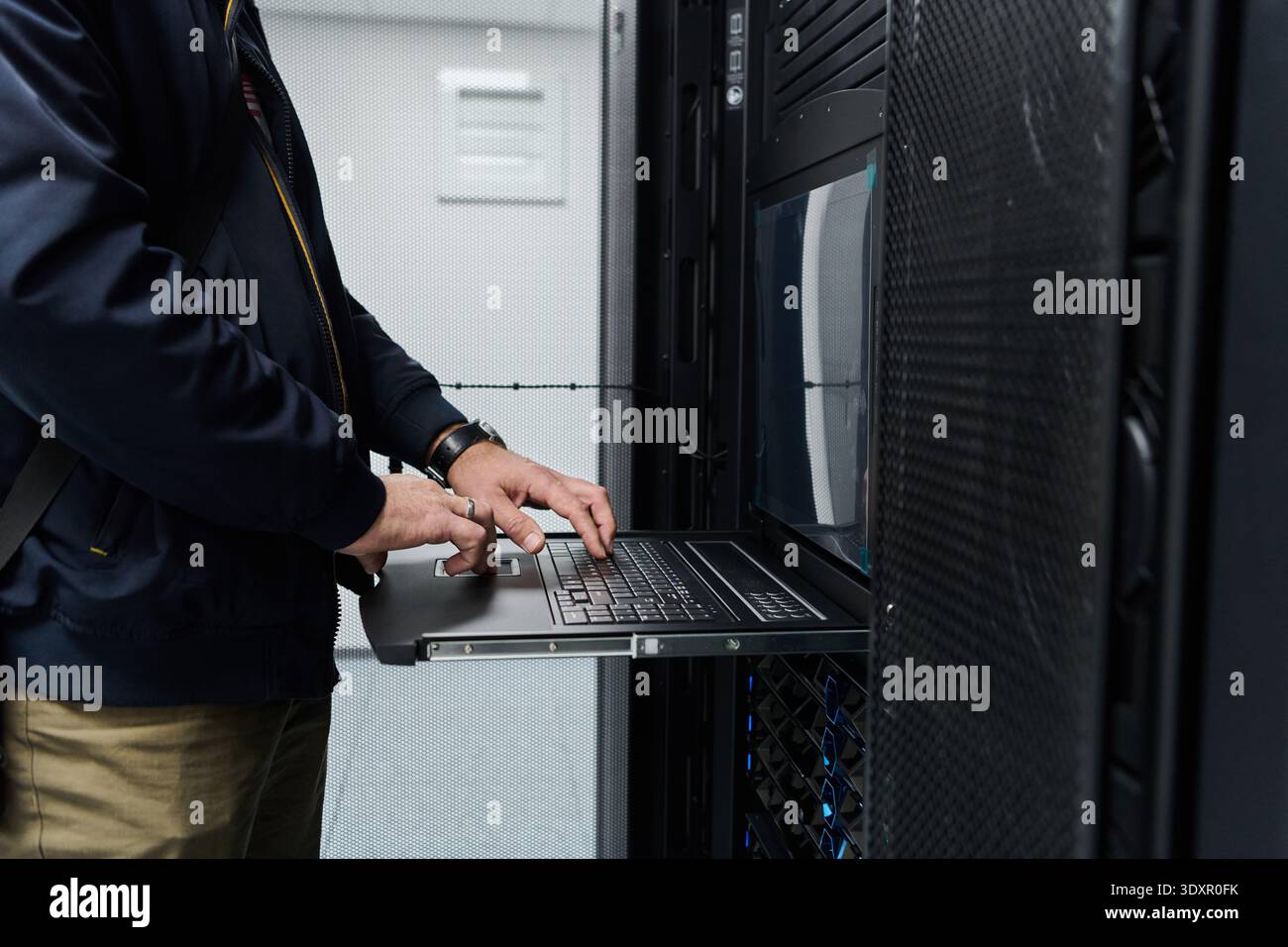 Data center technician working on a rack server using a slide-out laptop console Stock Photo