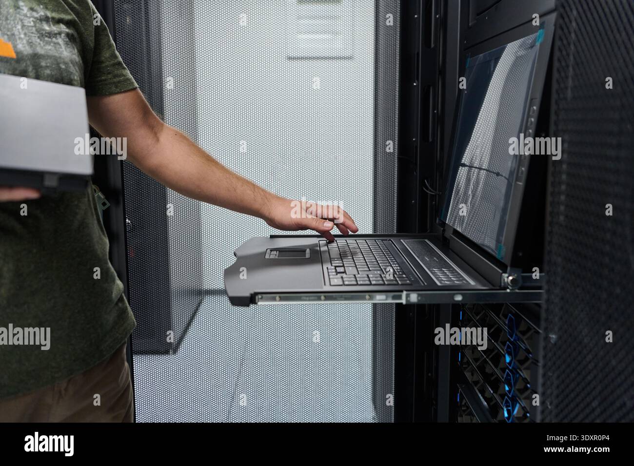 IT technician working on rack-mounted console laptop in a data center server room Stock Photo