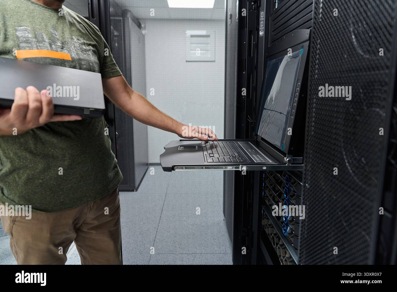 Data center technician using rack console laptop for server maintenance and IT network troubleshooting Stock Photo