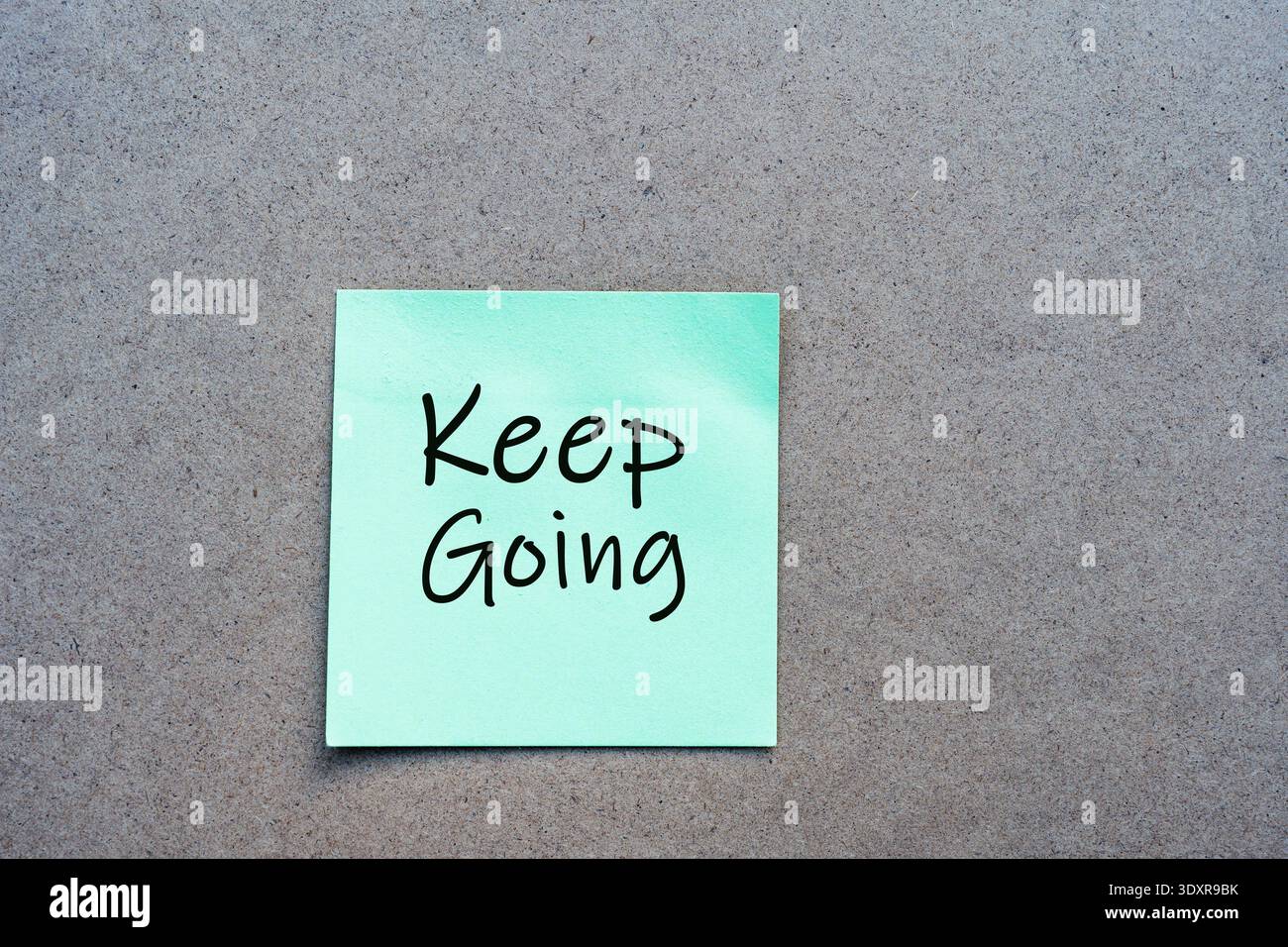 Motivational "Keep Going" message handwritten on a green sticky note. Concept for perseverance, continuous effort, and progress Stock Photo